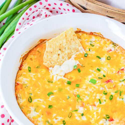 hot corn dip with cream cheese with a tortilla chip dipped in the dish