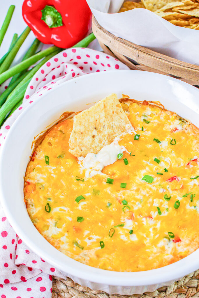 hot corn dip with cream cheese with a tortilla chip dipped in the dish