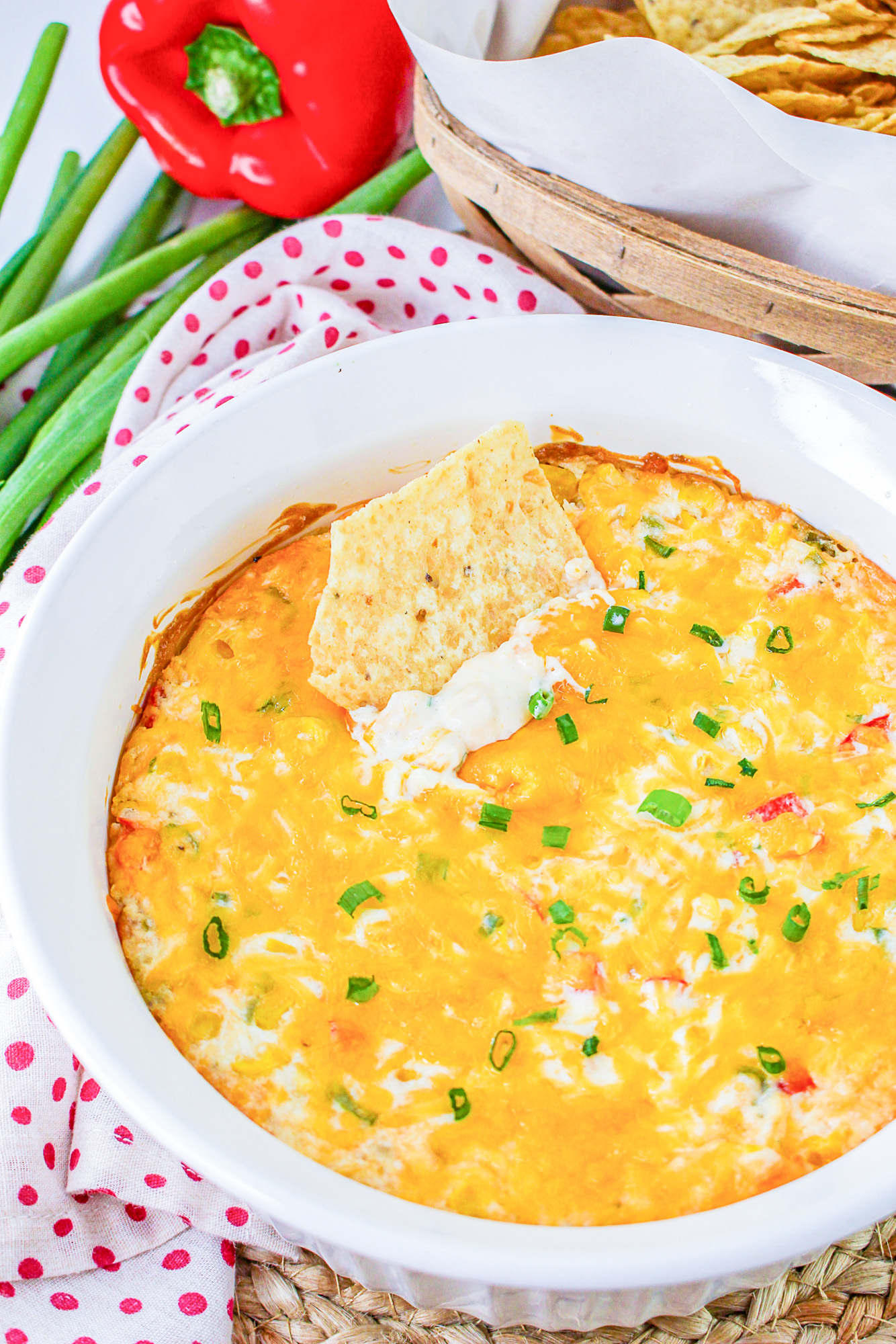hot corn dip with cream cheese with a tortilla chip dipped in the dish