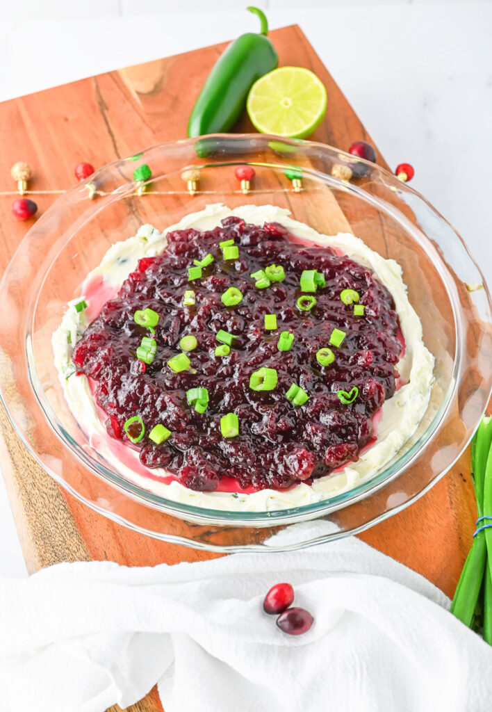 festive cranberry jalapeno cream cheese dip in a glass pie plare with holiday decorations