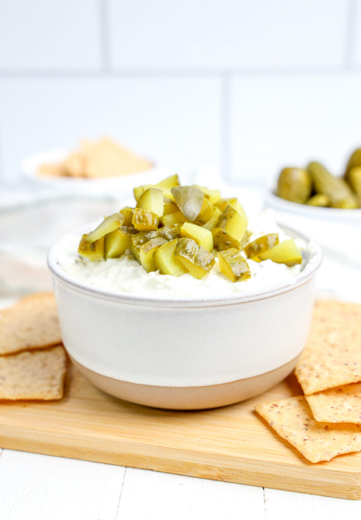 chopped dill pickles layered on top of dip with tortillas on the side