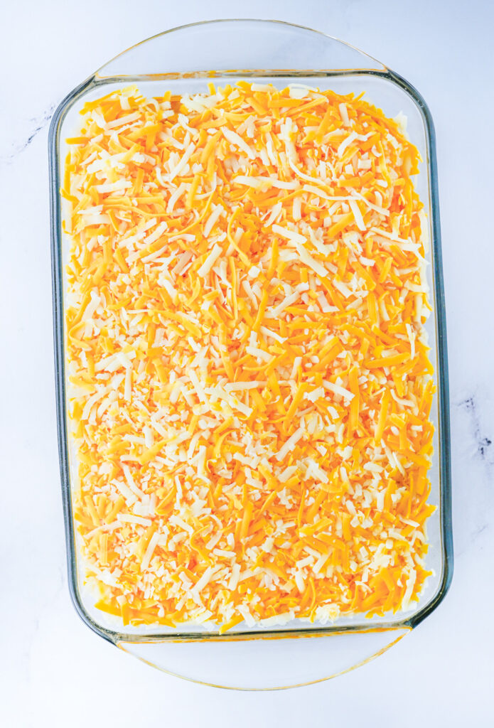 bean dip topped with shredded cheese in a casserole dish