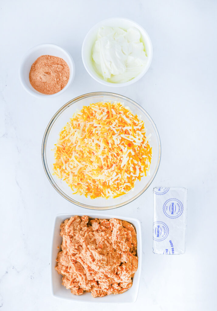 taco seasoning, cream cheese, sour cream, refried beans and shredded cheese on a counter