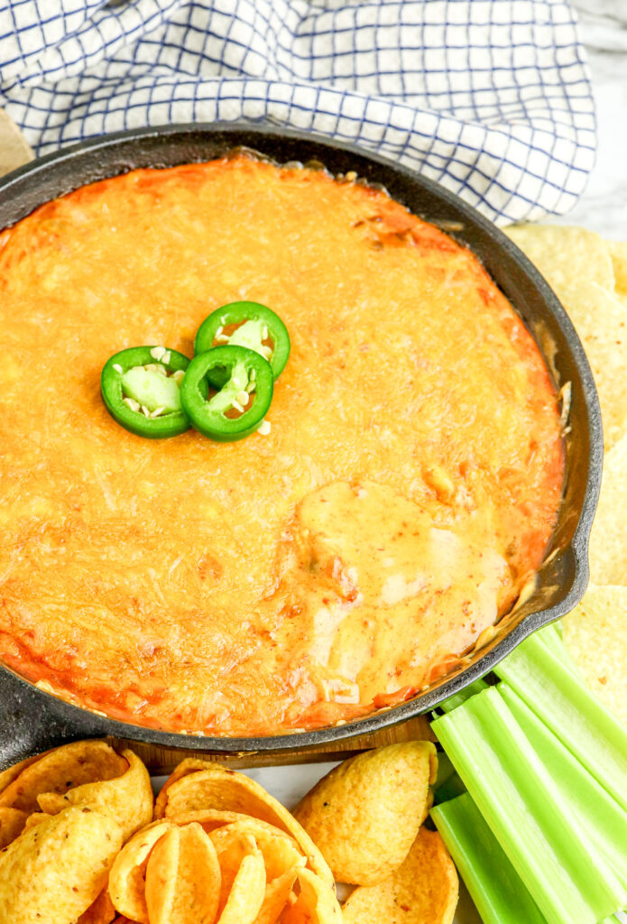 fully cooled chili cheese dip in a cast iron skillet with jalapeno garnish