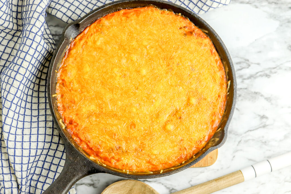 melted cheese on top of cheese dip in a cast iton skillet