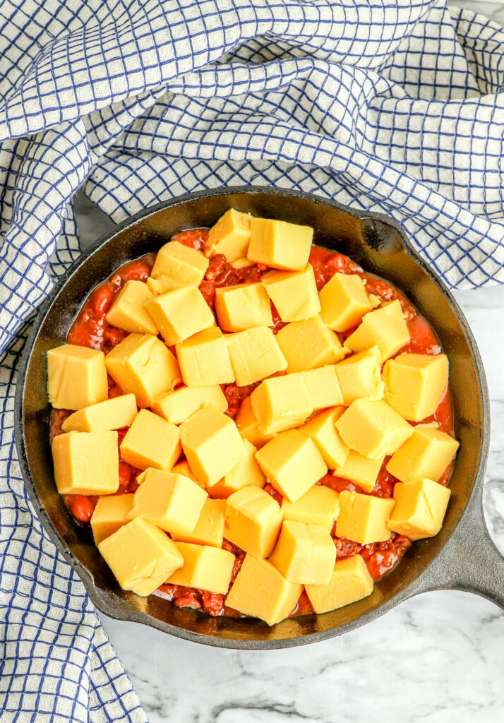 hormel chili and velveeta cheese cubes in a cast iron skillet