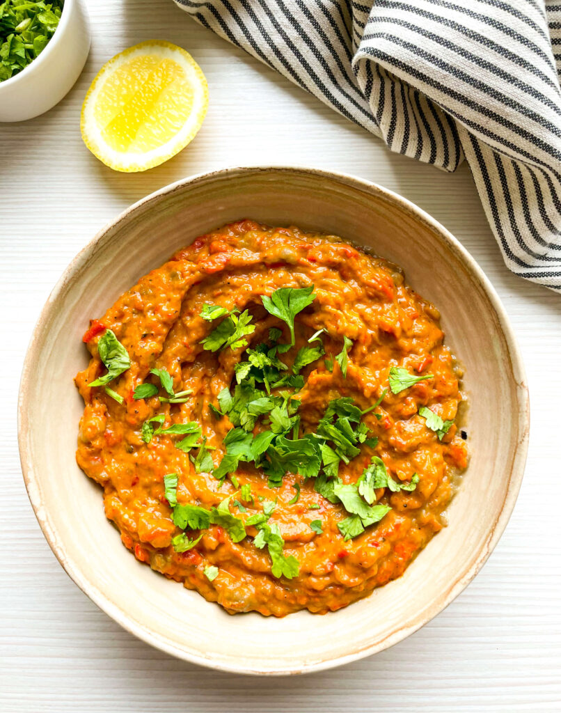 up close shot of zaalouk with parsley garnish and lemon on the side