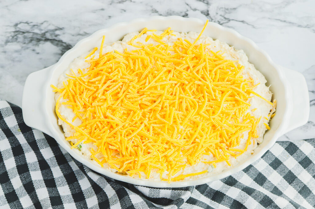 shredded cheddar cheese on top of crab dip ready for baking