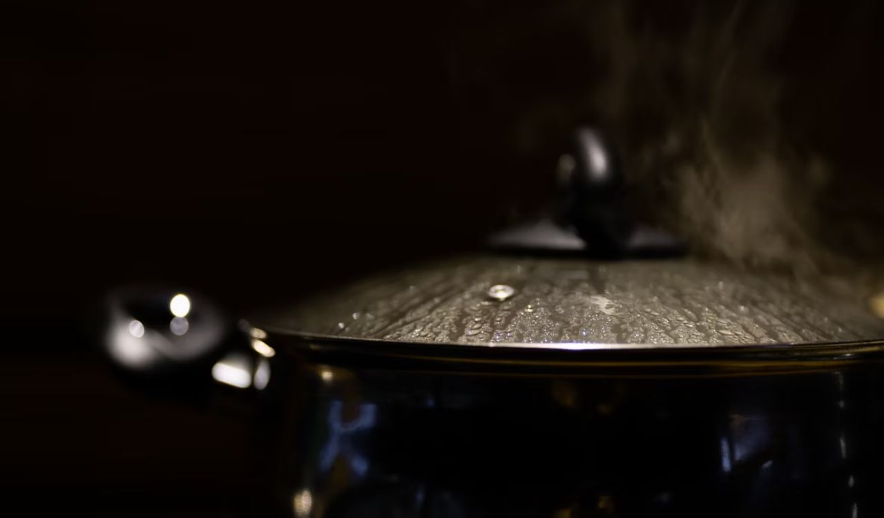 A boiling pot with steam coming out of it.