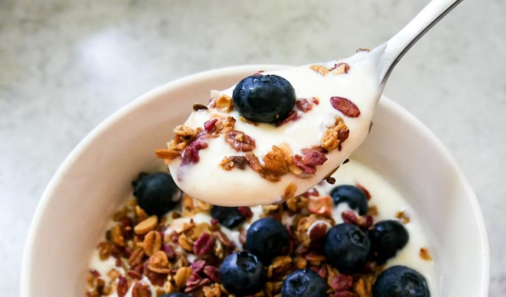 A bowl of granola with yogurt and blueberries