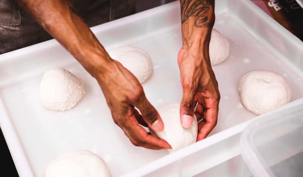 A closeup of a person putting dough in container
