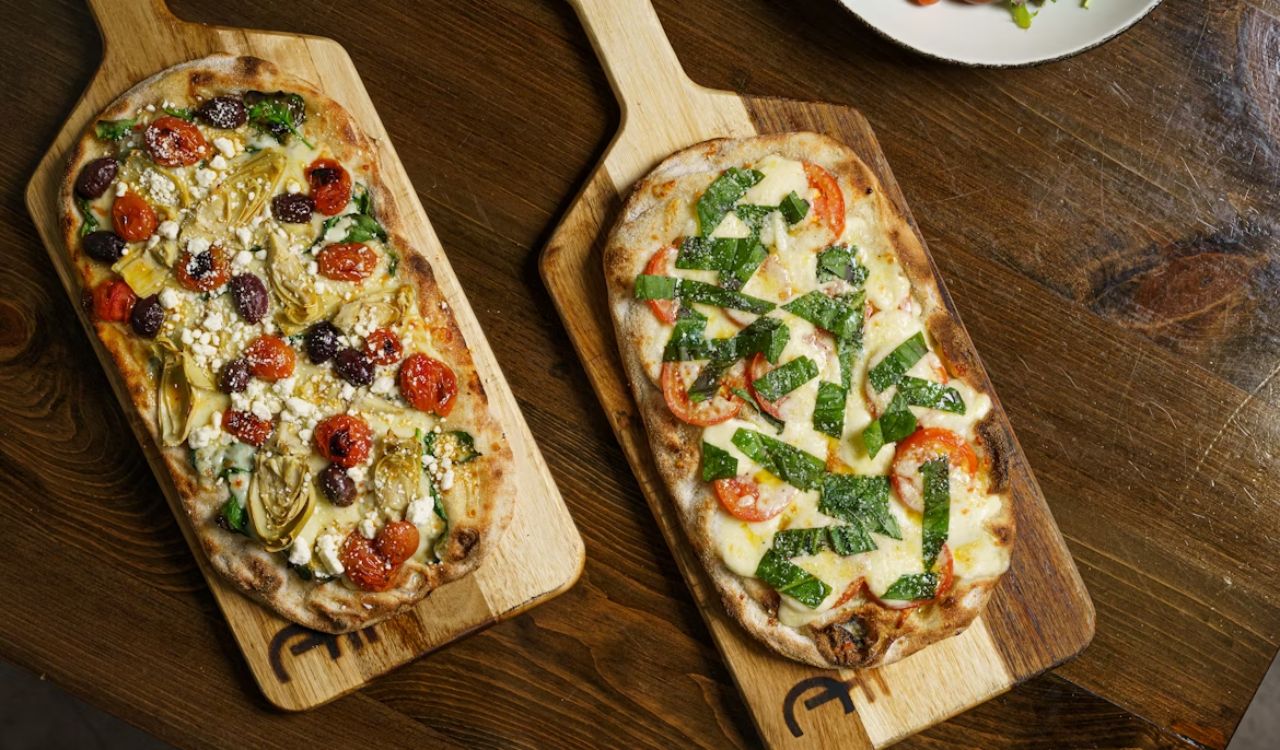 A couple of flatbread pizzas sitting on top of a wood board