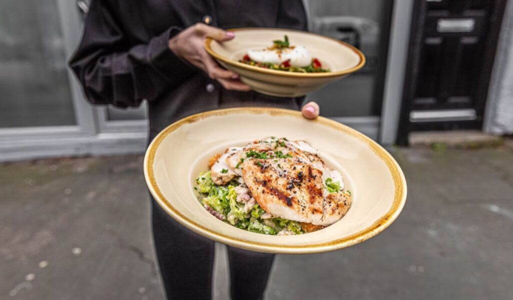 A person holding two plates of salad