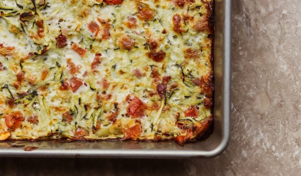 A square casserole dish with cheese and vegetables