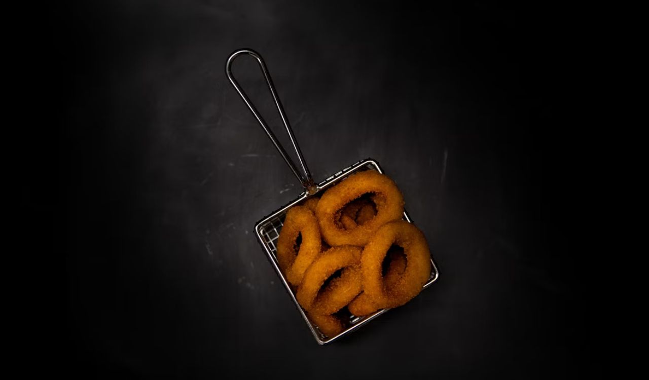 A square metal container filled with onion rings