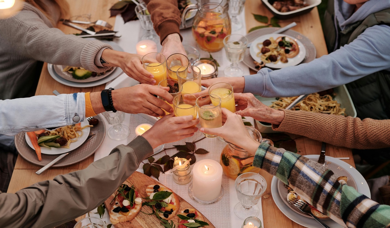 Faceless people toasting with glasses at dinner