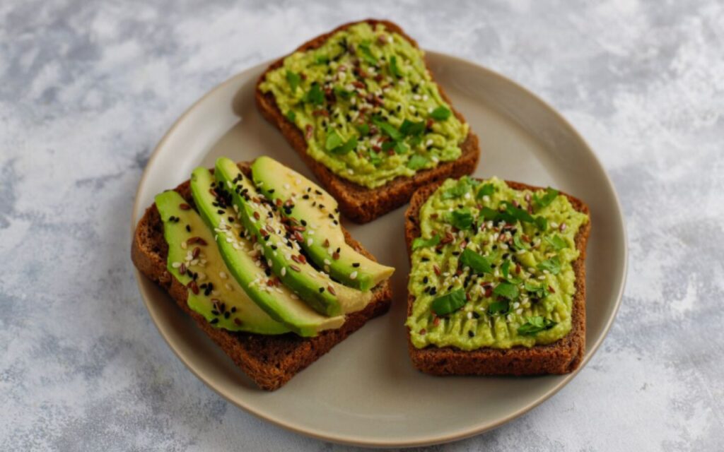 Avocado open toast with avocado slices, lemon, flax seeds, sesame seeds