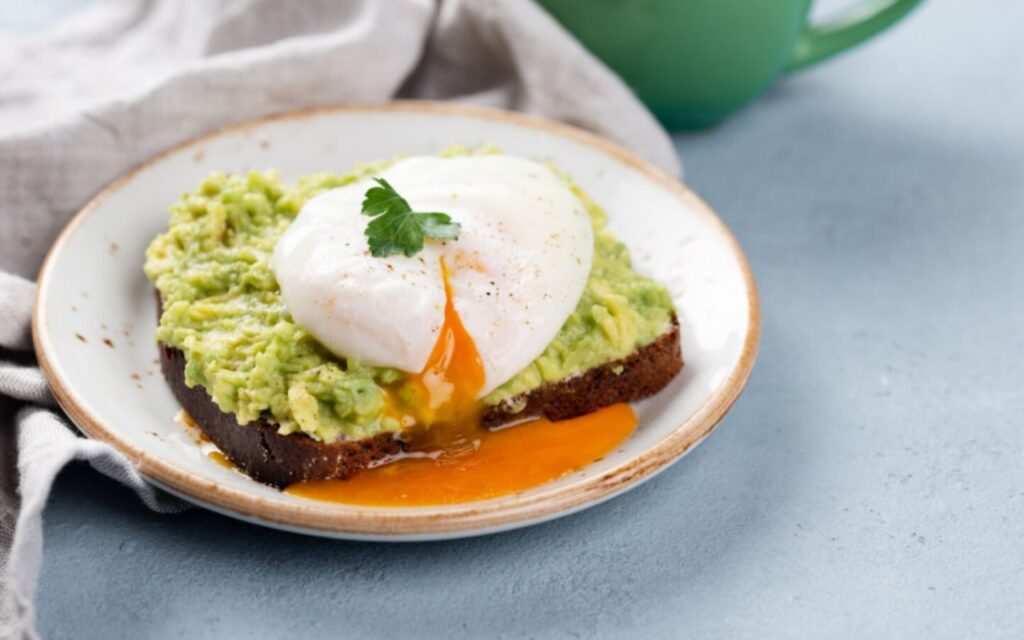 High angle of avocado toast with runny poached egg on top