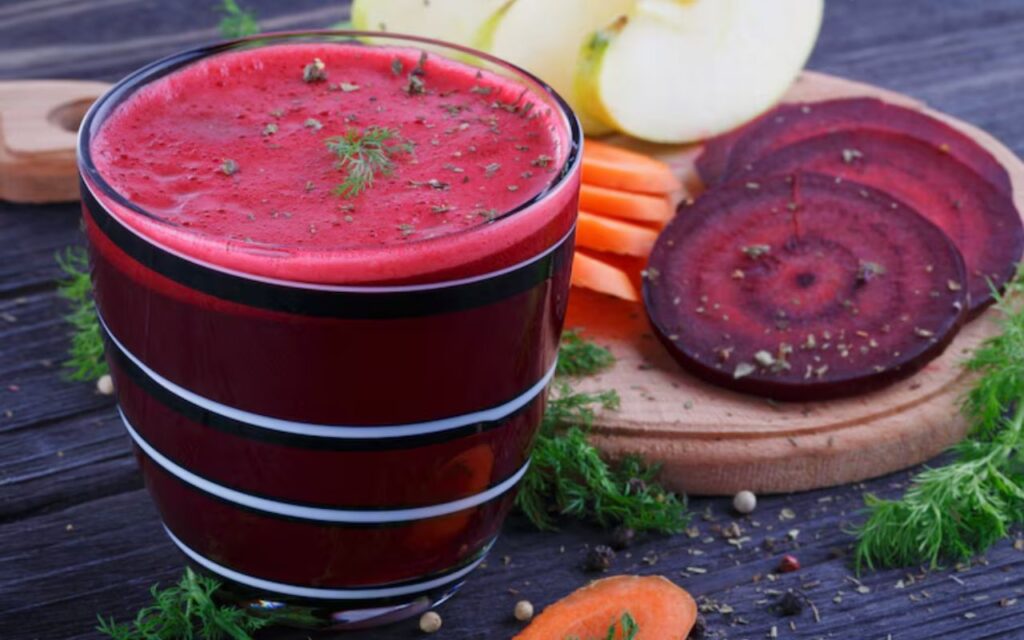 Beet juice in a glass with carrot and apple slices