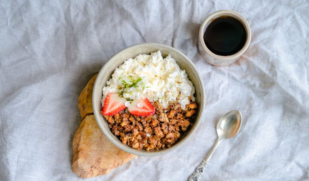 Bowl of Granola and Cottage Cheese Decorated with Slices of Strawberry and Flowers