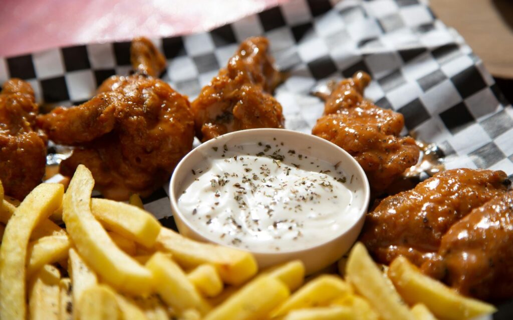 Buffalo chicken wings with fries and a cup of ranch/blue cheese dip on a checkered tray