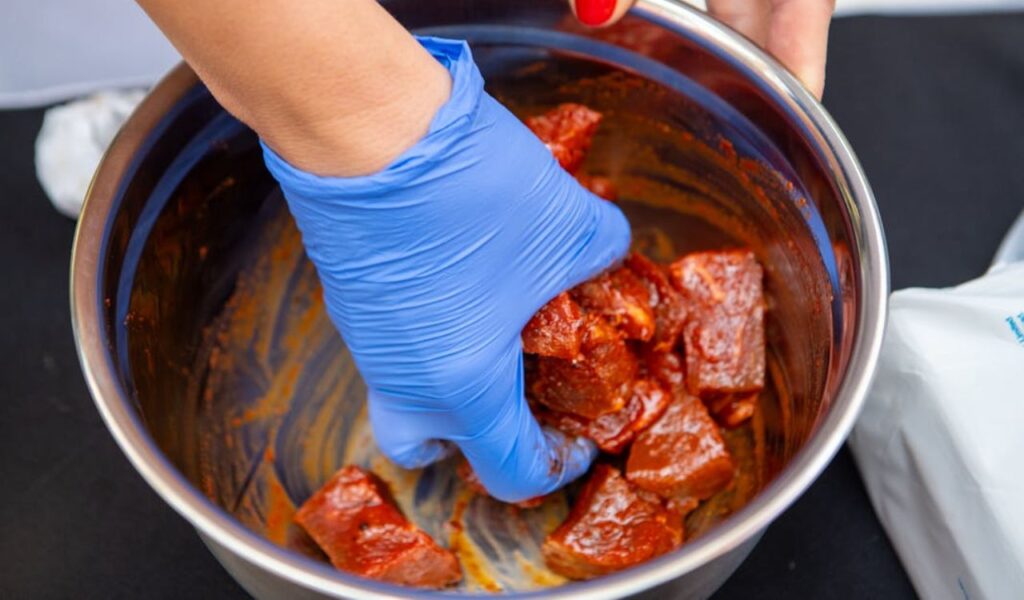 Chef preparing marinated meat in kitchen