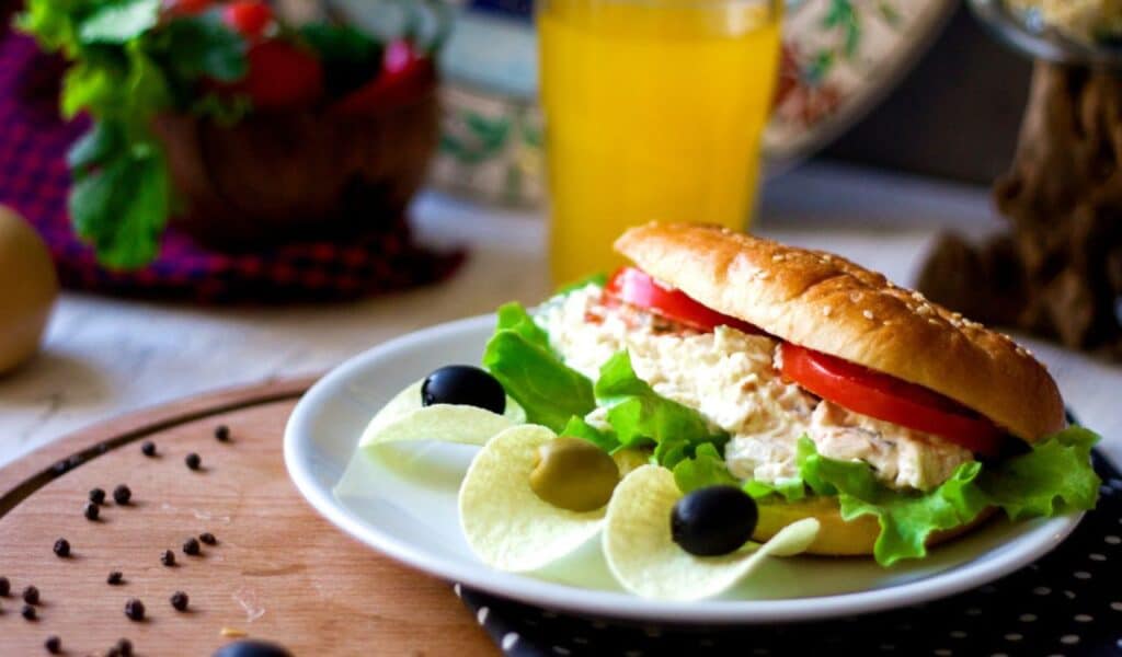 Sandwich with creamy salad and chips with olives