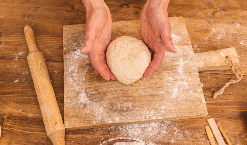 Close-Up Photo of a Person's Hands Holding a Piece of Dough