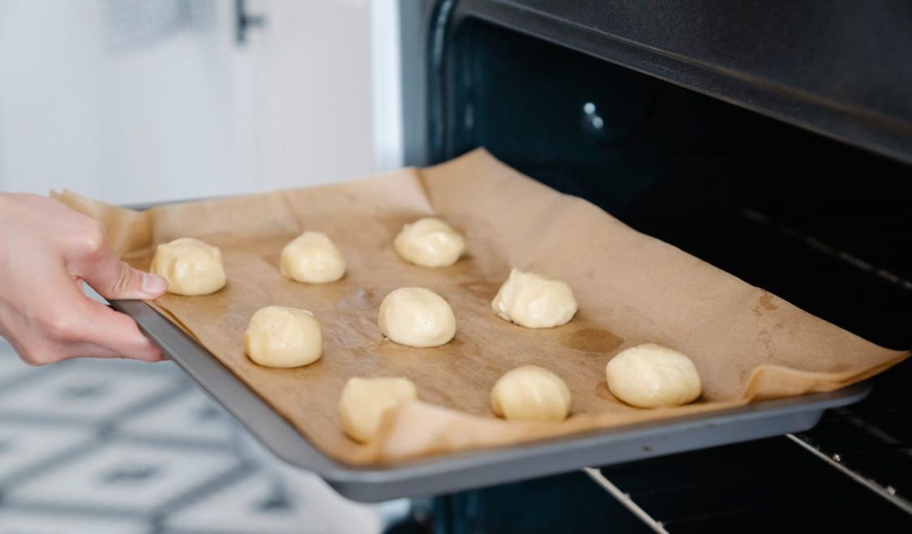 Close Up of Hand Putting Pan with Pastry into Oven