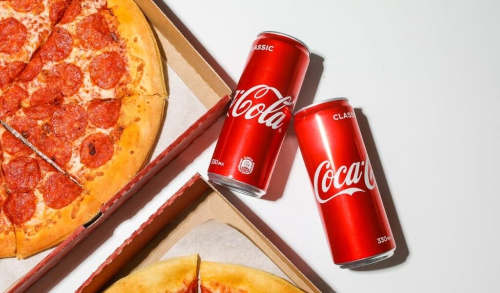 Coca Cola cans beside pizza