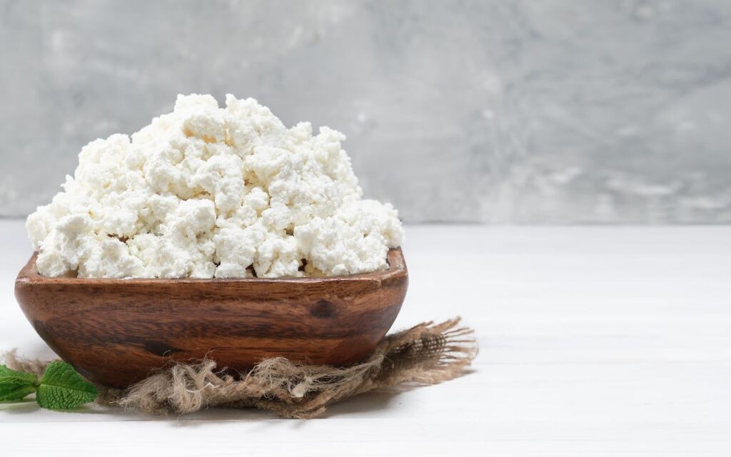 Bowl of fresh cottage cheese on a wooden surface
