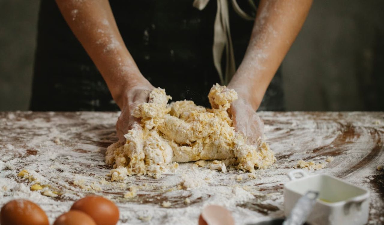 Crop cook kneading dough at table