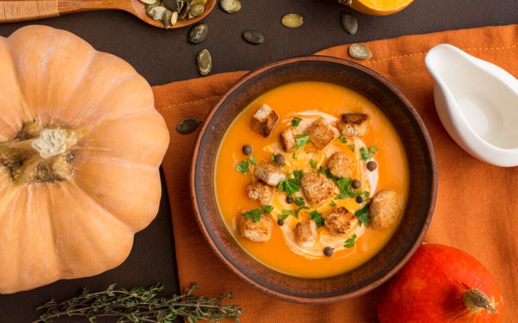 Bowl of curried butternut squash soup with croutons and herbs