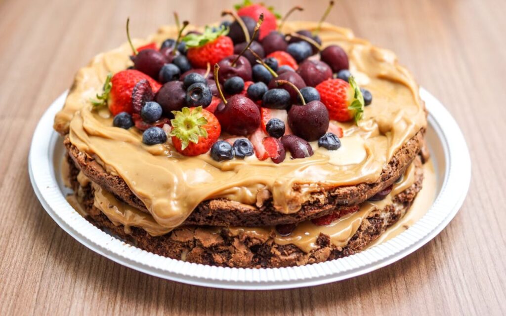 Layered chocolate cake with caramel frosting topped with fresh berries