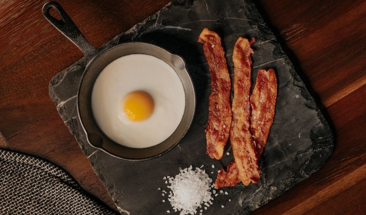 Egg and bacon on black plate