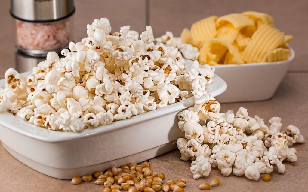 Bowl of plain popcorn with potato chips in background