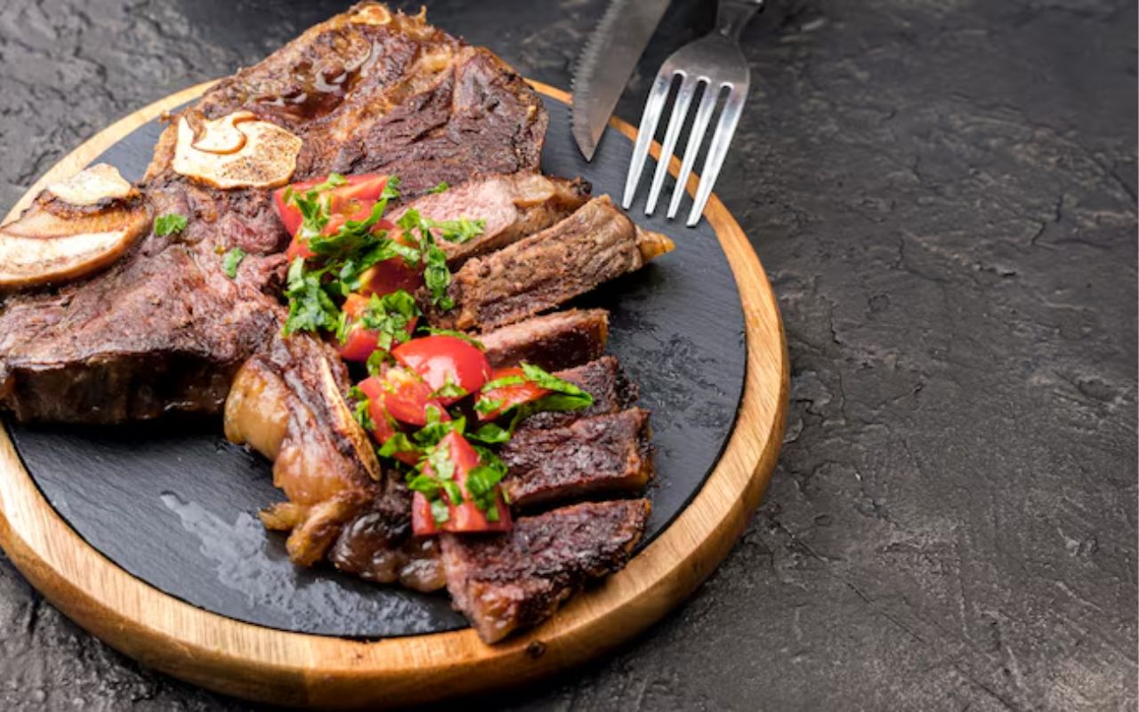 Sliced steak with cherry tomatoes and herbs on a round board