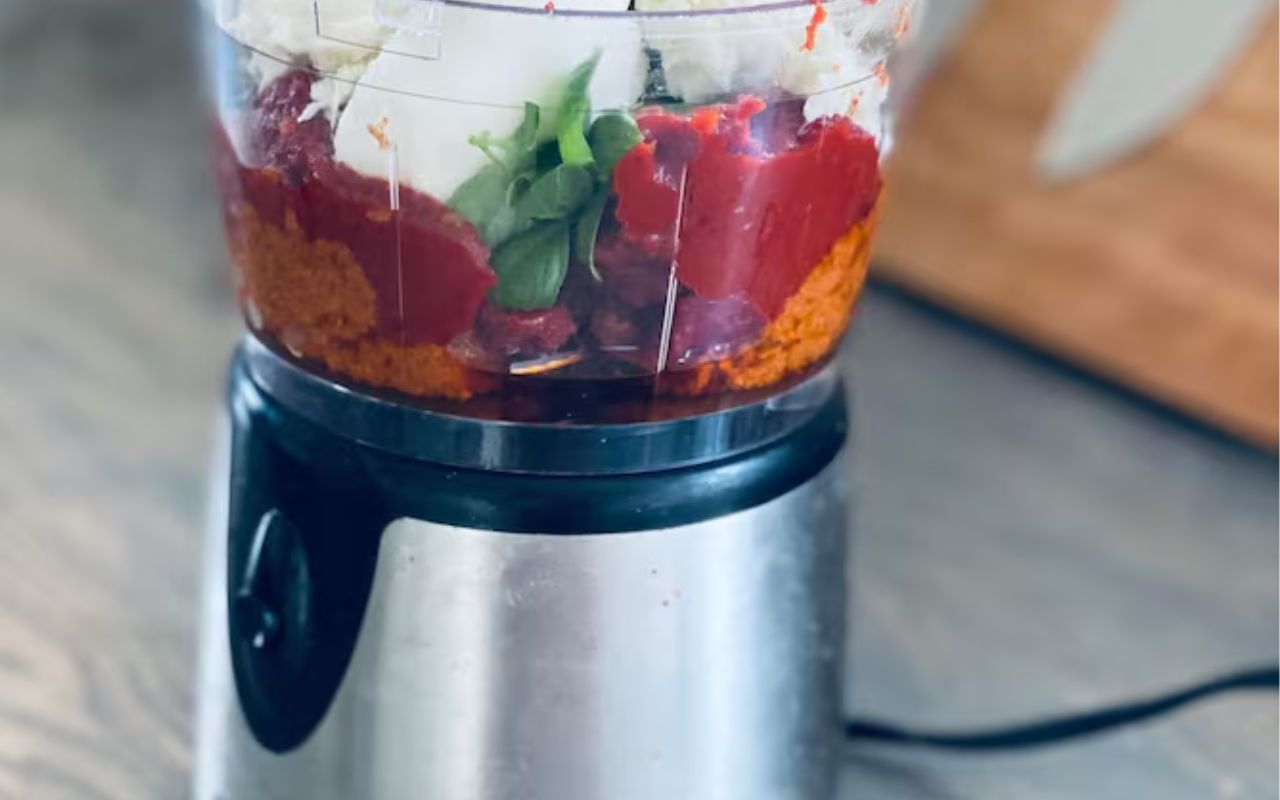 Food processor with tomatoes, greens, and cheese inside