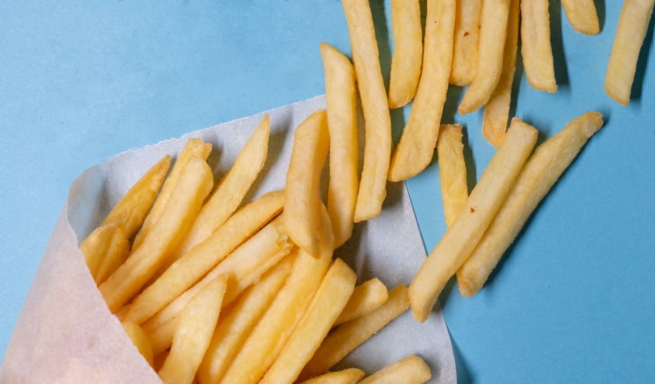 Fried potatoes in paper on blue background