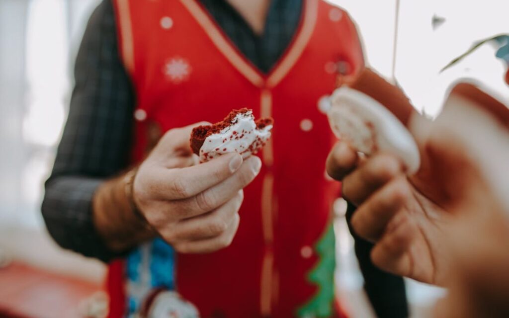 Person holding a bitten red velvet cookie with white icing