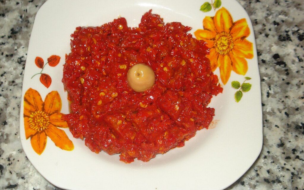 A plate of harissa, a red chili paste, with a single olive in the center