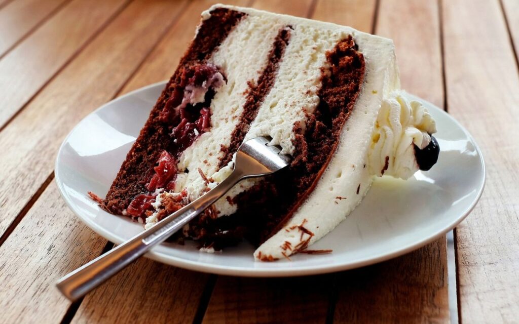 Slice of layered chocolate and cream cake with cherries