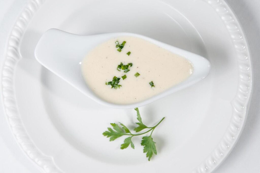 Tasty Bechamel sauce or white sauce with fresh greenery.