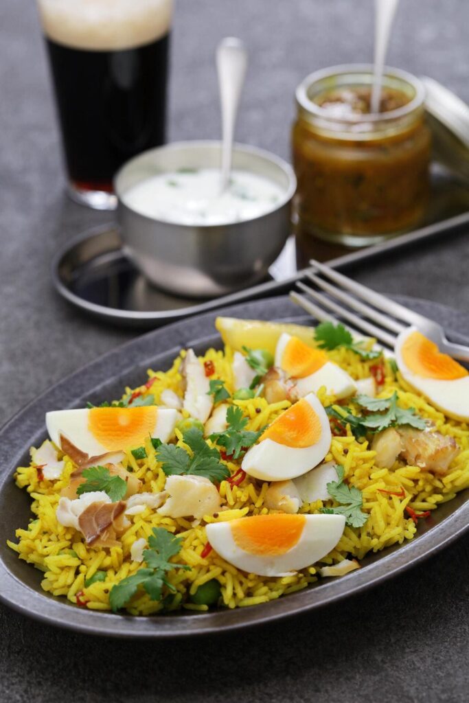 A bowl of kedgeree with rice, fish, boiled eggs, and herbs.