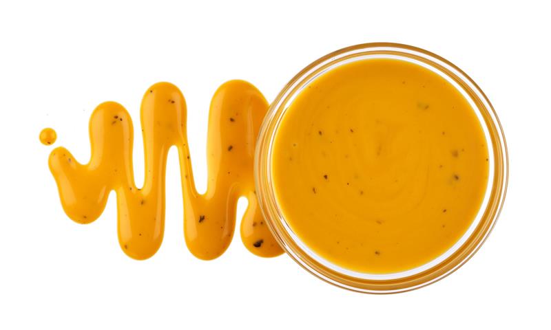 Honey mustard sauce. Splashes and spilled salad dressing isolated on white background with clipping path.