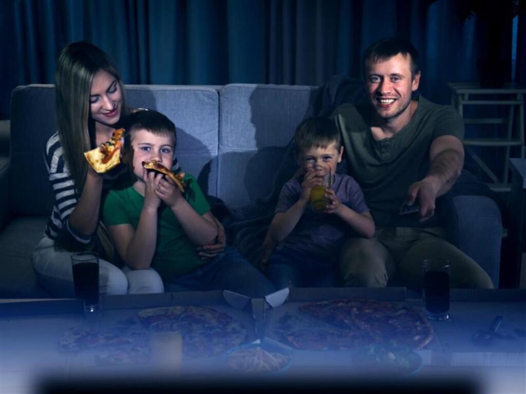 Happy lovely family watching TV with pizza