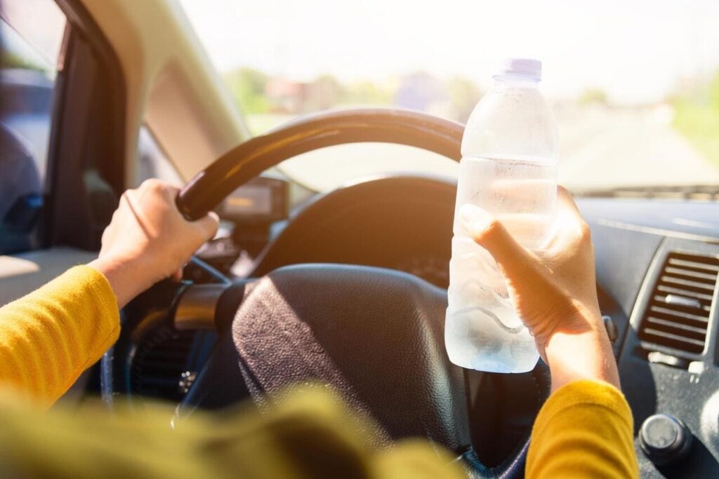 woman holding a water bottle for drink while driving the car in the morning during going to work on highway road