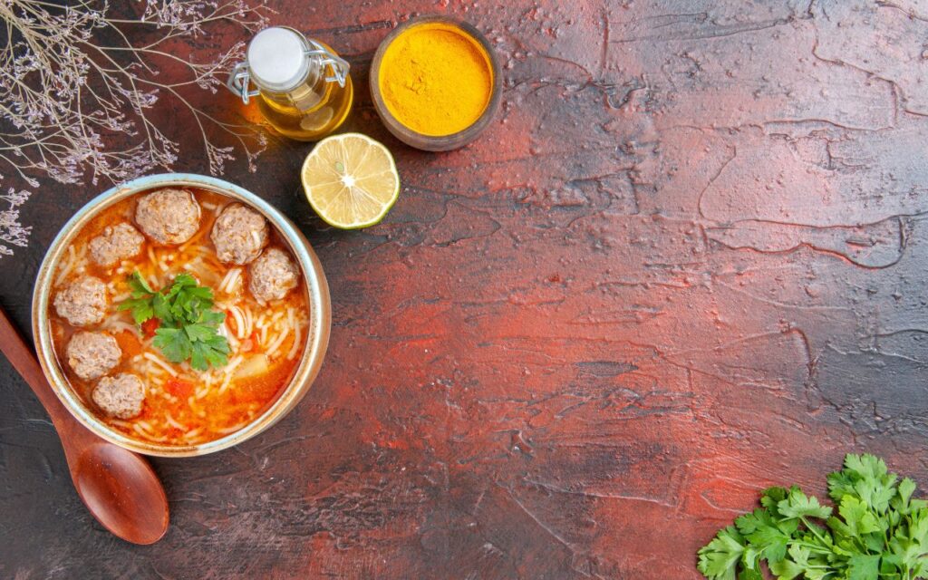 Bowl of miso chicken noodle soup with meatballs, garnished with parsley