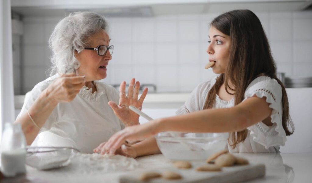 Pensive grandmother with granddaughter having interesting conversation while baking together
