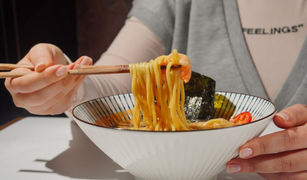 Person Enjoying Delicious Ramen with Chopsticks